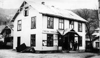 Fyresdal Handelslag i Folkestadbyen. Bygningen bordkledd utvendig 1925. Breifonn i bakgrunnen til venstre, Øystad til høgre.Foto Olav S. Nyli