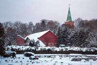 Stabburet og driftsbygningen med kirken i bakgrunnen. Foto: Leif-Harald Ruud (2018).