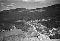 Vi ser tettstaden Øyane med diverse bygningar og gardane Veum oppe til høgre. Foto Widerøe