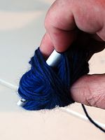 Nøstinga er i gang. Magebeltet er lagt i midten, så vet man at at har den når nøstet er tomt - der finnes opplysninger om garnet og vaskeanvisninger, noe som det er viktig å ta vare på. To fingre holdes inni nøstet, så det ikke skal bli for stramt - ellers kan garnet i midten bli klemt.