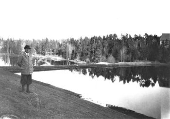 ADAM BAARSRUD VED NYDAMMEN ca. 1920. I gamle dokumenter også betegnet som "isdammene på Engen". Dammene ble anlagt av Thorvald Baarsrud 1895-1896. Med sin nære beliggenhet til sjøen ble de etterhvert de viktigste isdammene. Det var her den siste isen på Nærsnes ble skåret i februar/mars 1961. Til høyre sees bygningene på gården Søndre Nærsnes. (Foto fra Knut Baarsrud)