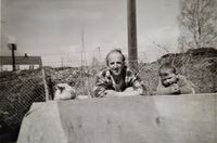 Westlie, Lindheim, Hjellum 1963 - Annar, Arne ved plankestabelen. Dyrehold - verpehøne. Engvillaen i bakgrunnen. Foto: Elida Westlie