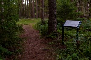 Informasjonsskilt ved en sti på vei til kulturminnet Tingplassen i Lindesnes.