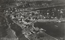 Flyfoto fra Sandvika hvor brua er under bygging, rett til venstre for rådhuset, midt på bildet. Foto: Nasjonalbiblioteket (1933-1934).