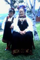 Bilete 14: Anne i full festbunad utanfor Vindegg, med fjøset i bakgrunnen. Jentebunaden til barnebarnet har truleg gått i arv. Foto: Ingebjørg Vindegg, om lag 1967.