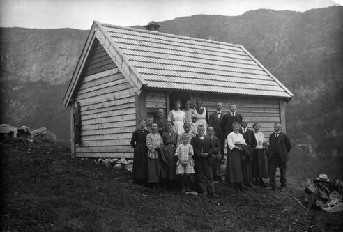 Ei gruppe lærarar ståande forran eit lite støylhus. Svart-kvitt foto.