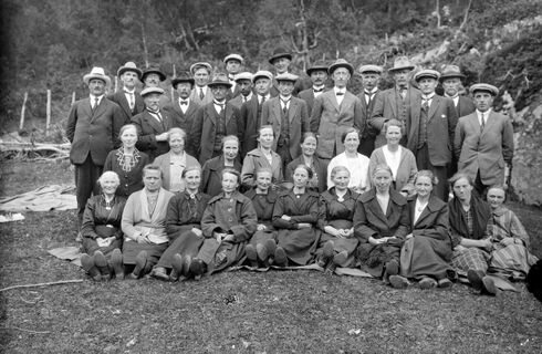 Svart-kvitt gruppebilde av lærarar. 18 damer sitt forran, medan 19 menn står bak dei. Damene har kjolar eller skjørt, dei fleste med jakkar, frakkar eller sjal over. Herrane har vest, frakk og hatt eller lue.