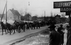 Foto tatt 11. april 1940 foran Sverre Damhaugs forretning. Fotografen står med Elisa Gierløffs forretning rett til høyre for seg. Småbruket Lillebak ligger på motsatt side av Strømsveien.