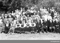 Bilete 8: Eldrefest utanfor Hol menighetshus i Holet. På fyrste rad sit gardbrukarar og gardkjerringer i hallingklede (Anne lengst til venstre av dei fire). På raden bak har nokre av kvinnene festbunad (blant dei Anne si syster Ambjørg) med lue eller skaut. Foto: Johannes K. Brye, 1961.