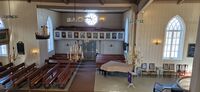 Elverhøy kyrkje sett frå søre galleri. Ein ser fire av ljosekronene, m.a. den største nærast koret, og den mest ornamenterte i midten. Foto: Thomas Erik Andreassen (2026)