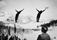 Sverre og Alf i et dobbelthopp under åpningen av Bjørngaard Hill, Snowbasin 16. februar 1941. Det blir strødd roser i unnarennet.