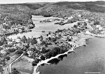 Flyfoto av Båtstø 1948. Is ble fremdeles produsert fra isdammen til venstre. Fylkesveien ligger i samme trasse som i dag (2023) tvers over jordet bak isdammen. Kort avstand for isen over til Lasteberget som stikker ut i fjorden. Den nye moloen i Båtstø var ennå ikke bygget. Blåhellaveien ligger helt til venstre på bildet (Fotograf ukjent) .