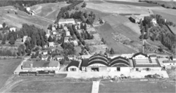 Kjeller flyplass med hangarer og Kjeller flyfabrikk 1943. Lenger bak Flyvebyen, Dompa-anlegget og Kjeller gård.