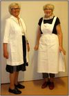 Uniformsforkle. Ragnhild (t.v.) har på seg forkledet som blei bruka på aldersheimen tidlegare. Astrid viser forkledet til ei typisk sjukepeleieuniform.