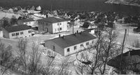 Funkstellet i Kaarbøåsen ble etablert i 1940 og ble til Harstad Radio i september 1945, og nedlagt i 1991. Nærmest ses tre tyskerbrakker hvorav den til venstre var sender- og mottakerbrakka. Vis a vis sender/mottakerbrakka står hovedhuset som fra høsten 1945 huset ansatte ved Harstad Radio. Til venstre for hovedhuset står "bestyrerbrakka", der telegrafbestyrer Bathen bodde med sin familie. Et stykke ned i bakken bak hovedhuset og den midterste brakka ses transformatorhuset som hadde "basseng" på taket. Bak/til venstre for transformatorhuset står huset som seinere fikk adresse Eineberggata 20, bygd og eid av Birger Hanseth, sveiser på Kaarbøs Mek. Verksted. På sletta nedenfor transformatorhuset ses de fire tomannsboligene - lektorhusene, satt opp i 1947/1948 for å huse lærerkrefter til det som seinere ble til Heggen videregående skole. De ble populært kalt "Ludobrikkene" fordi de var malt i rødt, grønt, blått og gult, i tillegg til at de var nærmest kvadratiske. Litt til høyre for midten av bildet ses Harstads rådhus som sto ferdig i 1953.