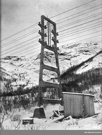 Pendelmast nr. 17 i betong på kraftoverføringen fra kraftverket til Haugvik, her ferdigstilt og ledningsnettet montert. Foto: Bernt Lund/Nordlandsmuseet (1920).