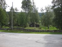 Vi ser ein del av bygningane til Fyresdal bygdemuseum mellom gravhaugar i Øyskogen. Vegen er Meieribakken. Fotograf: Olav Momrak-Haugan. 2010