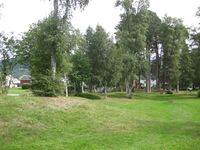 Husrekka i bakgrunnen er i Folkestadgata. Til venstre, nord for muren og Meieribakken, skimtar ein nokre av gravhaugane mellom husrekkene der. Fotograf: Olav Momrak-Haugan. 2010