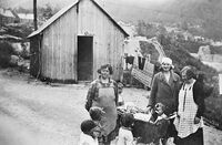Kvinner og barn framfor vaskehuset som høyrde til brakkebyen i Tyssedal. Kraftmuseet - Norsk vasskraft- og industristadmuseum, ca. 1931.