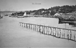 Fotografi fra 1900-1905. Isrenne fra isstabelen på Mellomstranda ut i Nærsnesbukta for lasting av Isblokker. Propsebrygga skimtes langs siden av båten til høyre. Brygger lags land bak dampskipet. Et transportbånd er ved stein/grushaugene ved det gamle steinbruddet. I bakkant er det jakter fortøyd ved land. Lengst ute til venstre ankommer rutebåten. (Postkort; Arve Solli)