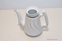 Kaffekanne i porselen. Kannen er støpt. Fargen hvit med stillisert gulldekor. H: 21cm L: 4cm. Kaffekannen er i god tilstand, men mangler lokk. Kaffekannen er uten feil. Håndtaket har dekor i porselen. Røyken Historielag kornmagasinet 2. etg./ Mottatt 1987 / Giver Kristoffer Flater, Røyken / Katalogisert 06-05-2004 av FCHR