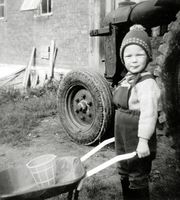 Kai Hansen leker foran låven og traktoren i Paulsberg. Foto: Ukjent, ca 1969