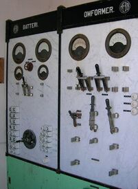 Kontrolltavle i marmor på Katterat transformatorstasjon med store viserinstrumenter og åpne knivbrytere, og er delt opp i felt for batteri og omformer, levert av NEBB. Foto: Åsmund Wie/Jernbaneverket
