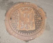 Kumlokk med Holmestrands byvåpen. Byvåpenet ble tegnet av Andreas Bloch i 1898.