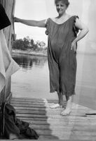 Kvinne i badedrakt. Trolig Veras mor. Kanskje hører veggen hun støtter seg på til et badehus.