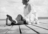 Kvinne solbader på brygge.