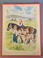 Puslespill i ca. 50 deler laget av tykk kartong. Motivet er en jente som sitter på en hest og ved siden av står det en gutt og holder i grimen. Produksjon: ca. 1960–1964