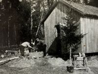 27. Levorstad. Vedkapping, og slipestein forran verkstedet..jpeg