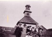 Lystig selskap foran klokketårnet omkring 1920.