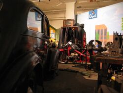 Strømmen Storsenter (3) svart veteranbil, rød motorsykkel, arbeidsbenk, klær, radio, foto Steinar Fjeldvang.