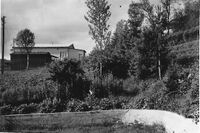 Marinefunkstelle Harstad som ble etablert i Kaarbøåsen av den tyske okkupasjonsmakten sommeren 1940, ble overtatt av Telegrafverket i september 1945. Bildet viser noe av det som ble stående etter at Harstad Radio flyttet til toppen av Harstadåsen i 1948. Vi ser den tyske senderbrakka med en garasje foran. Fotograf Steinar Pedersen står i 2. etasje i boligen som far Sigurd Pedersen oppførte og flyttet inn i høsten 1949. Foto fra 1965.