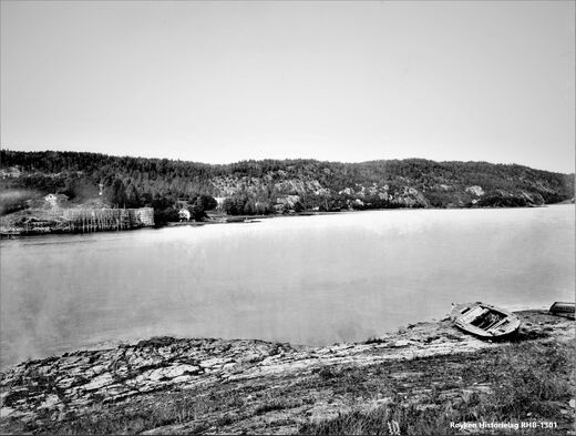 NÆRSNESBUKTA 1893-1898. Utsikt vestover i Nærsnesbukta sett fra stedet der Promhavn Slipp ligger i dag. Til venstre er en isstabel ved Bryggebakken. Bakenfor denne, til høyre, skimtes isstabelen på Graffodden. Dampskipet D/S Mimi (bygd 1883) i bakgrunnen ligger utenfor Nordstranden, der Amundsen Marina og båthavna ligger i dag (Foto fra AS Søndre Nærsnes, fotograf ukjent)