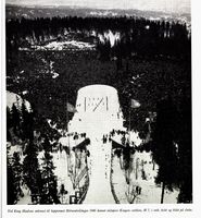 Ved Haakon VIIs ankomst til hopprennet Holmenkolldagen 1946 dannet skiløpere Kongens emblem H7 i rødt, hvitt og blått på sletta. Foto: Ranheim: Norske skiløpere : Østlandet sør, 1956