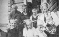 Anne og Ole med seks av ungane på trappa utanfor Osestølen. Her er familien pynta til fest. Anne med hette og truleg svart stakk. Ole har "hallingkleu" med sylvknappar. Kan biletet vera frå dåpsdagen til Sissel, som vart fødd i januar? Ukjend fotograf, 1925.