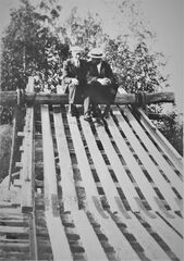 To personer sitter på bommen på isrenna, ca. 1924. Bommen ble brukt til å stoppe blokkene før de ble styrt ut til båten. Fra venstre: Karl Ramton (far til Hans Ramton) og hans svoger Christian Laheld. Fotograf ukjent.