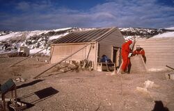 Paul Chaplin (i rød vinddress) i arbeid med nødvendig vedlikehold på Cape Adare i 1995.