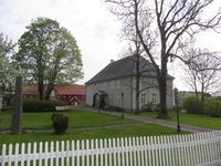 Prestegården ved Vestby kirke, med bautaen over Johan Herman Wessel i forgrunnen til venstre. Foto: Stig Rune Pedersen