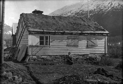 Svart-kvitt foto av eit eldre hus med torvtak.