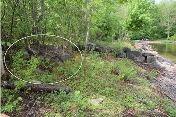 Til høyre sees det nordøstre hjørnet på isstabel-grunnmuren på Flatstranda. (som kyststien passerer over). Den innringende steinhaugen til venstre er restene etter et gammelt fortøyningskar (Foto Victor Iversen 2022)