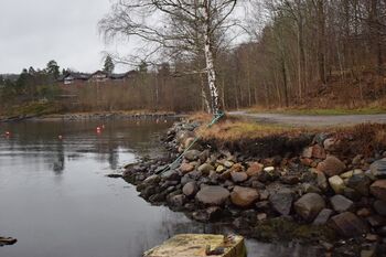 Går du kyststien fra Graffodden mot Nærsnes kan du, fra brygga til Røyken Seilforening, se at steinene til grunnmuren fremdeles ligger i en rett linje i vannkanten der Isstabelen på Bryggebakken lå. Lenger inn lå det brygge for lasting av is. (Foto: Victor Iversen 2020)