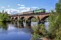 Et godstog fra Bergen i retning Oslo krysser Begna på steinhvelvbrua like øst for Hønefoss stasjon. Foto: Leif-Harald Ruud (2020).