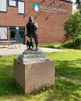 Statue ved Roald Amundsens videregående skole, Sofiemyr i Nordre Follo kommune. Statue er en kopi av Arne Vigelands statue fra 1972 ved Bålerud brygge på Svartskog, like ved Roald Amundsens hjem. Denne kopien sto tidligere i nærheten av Kolbotn stasjon, men ble flyttet til nåværende plassering da Oppegård videregående skole skiftet navn til Roald Amundsens videregående skole i 2012. Siri Iversen (2022).