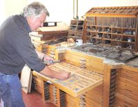 «Museumsbestyrer» Rolf Solsvik i gang med å stable blybokstaver i vinkelhaken. Akkurat slik det har vært gjort i flere hundre år. Gutenbergs oppfinnelse lever altså i beste velgående på Fenes.}}