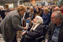 Statsminister Erna Solberg hilser på et av de aller eldste tidsvitnene, Ruth Goldstein, som deltok under seremonien i Oslo Rådhus. Ruth hadde flyktet med Carl Fredriksens Transport sammen med moren Elsa Schapow. Hun krysset grensen på sin 18-årsdag, 15. desember 1942. Faren og broren var blitt arrestert 24. oktober. Deres tragiske endelikt kom for en dag først etter krigens slutt.