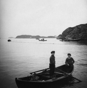 Skarvøyna med dei to husa bak. I båten frå venstre: Håkon Sjøvold og Kristian Kristiansen. Foto: Bildesamlingen Universitetet i Bergen (atelier KK)