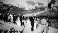 Bryllaupet til Minny og Edvard Eriksen (11b) i 1947. Det var vanleg at brurefølgjet gjekk i prosesjon frå kyrkja til heimen, der selskapet vart halde. Henry Uthaug (11a) spelar trekkspel. Kopper i bakgrunnen.
